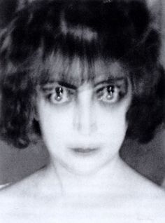 an old black and white photo of a woman's face with very large eyes