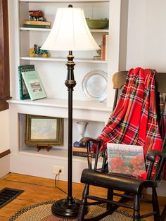 a rocking chair with a lamp on it in front of a bookshelf filled with books