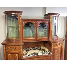 an old fashioned wooden china cabinet with glass doors and drawers on the front, along with marble flooring