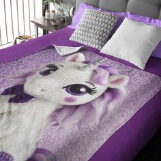 a bed with a purple comforter and pillows on top of it in a bedroom