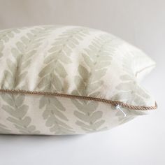 a close up of a pillow on a white surface with a brown cord attached to it