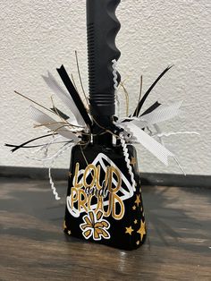 a black and gold bell shaped object on top of a wooden floor next to a white wall