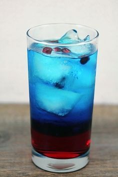 a blue drink with ice and cherries in it