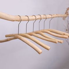 several wooden clothes hangers hanging on a white wall next to a branch filled with twigs