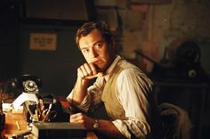 a man sitting at a desk with his chin resting on his hand and looking off to the side