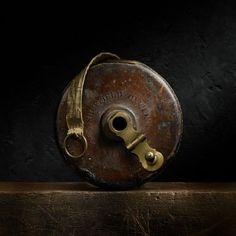 an old metal object on a wooden shelf with a yellow strap around it's neck