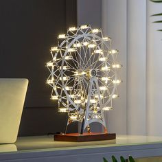 an illuminated ferris wheel on a desk next to a laptop