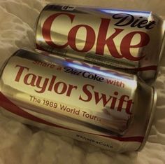 two cans of diet coke sitting on top of a bed