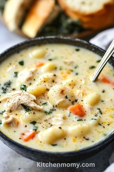 a bowl of chicken noodle soup with bread in the background