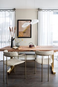 a dining room table with two chairs and a vase on the table next to it