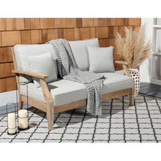 a white couch sitting on top of a rug next to a wooden chair and vase