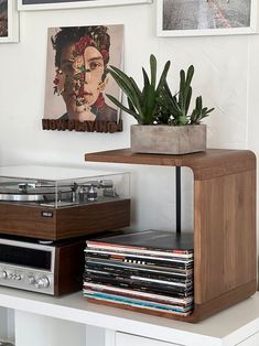 a record player sitting on top of a wooden shelf next to a potted plant