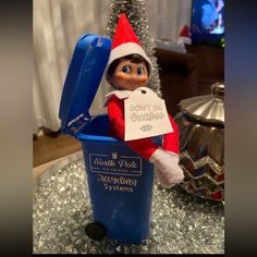 an elf is sitting in a blue trash can