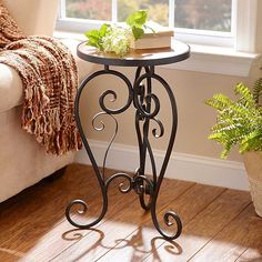 a small table with a plant on it next to a couch and window sill