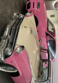 a pink and white car parked next to each other in a room with tile flooring