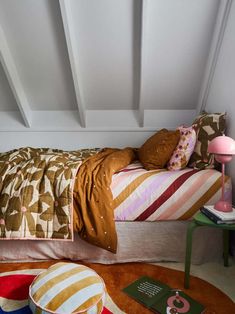 a bed sitting in the middle of a bedroom next to a table with a lamp on it