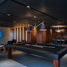 a pool table in the middle of a room with several lights hanging from the ceiling