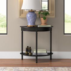 a blue and white vase sitting on top of a table next to a lamp in a room