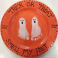 an orange plate with two white ghost faces painted on it and the words trick or treat smell my feet