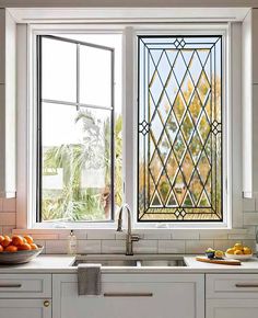 a kitchen window with fruit on the counter and in front of it is a bowl of oranges