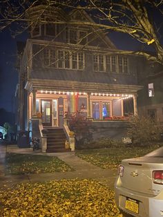 a house that is lit up at night with lights on the front porch and stairs