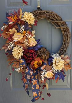 a wreath with flowers and leaves hanging on the front door to decorate it for fall