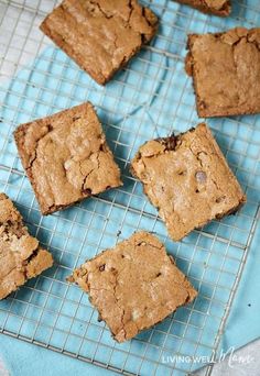 six brownies on a cooling rack with blue napkins next to them and one cookie in the middle