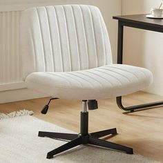 a white office chair sitting on top of a wooden floor next to a black table