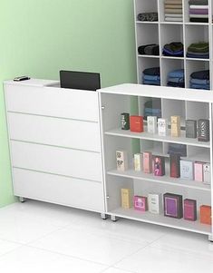 a white book shelf with many books on top of it next to a green wall