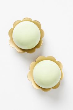 two white and gold flower shaped knobs on a white surface