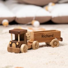 a wooden toy truck sitting on top of a white carpeted floor next to pillows