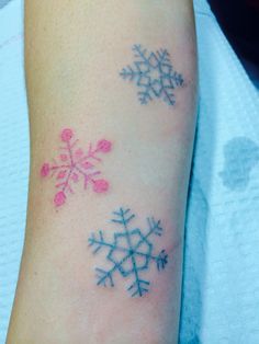 two snowflakes are on the arm of a woman with pink and blue ink