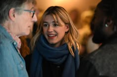 a woman standing next to an older man in a room with other people looking on