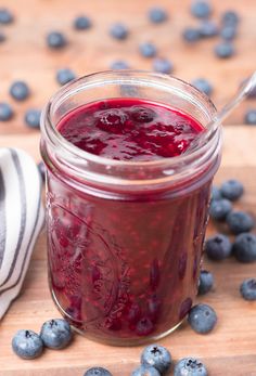 a mason jar filled with blueberries and the words quick & easy berry sauce on it