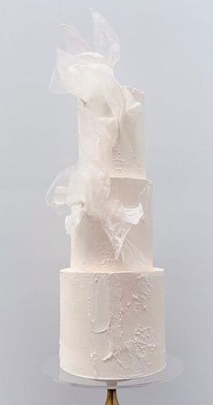 a three tiered white wedding cake on a stand