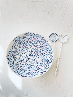 a blue and white plate sitting on top of a table next to a spoon with red dots