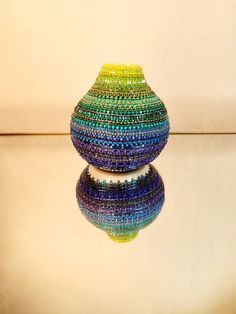 a multicolored vase sitting on top of a white table next to a mirror