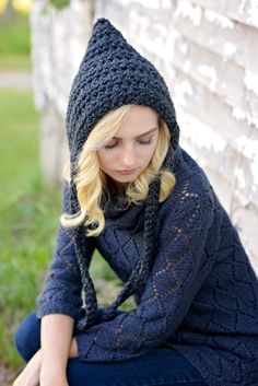 a woman sitting on the ground wearing a knitted hat