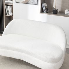 a white couch sitting on top of a carpeted floor next to a book shelf