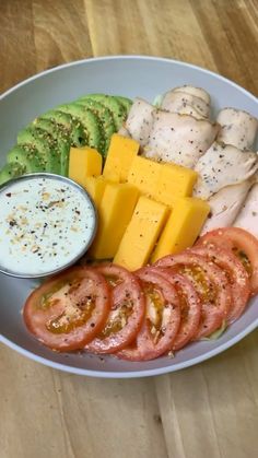 a white plate topped with meat, cheese and veggies next to a bowl of ranch dressing