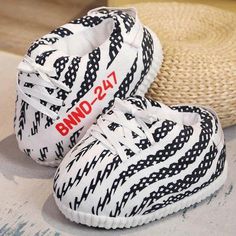 two white sneakers with black and red letters on them sitting next to a straw hat