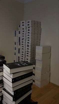 a stack of books sitting on top of a wooden floor next to a pile of boxes