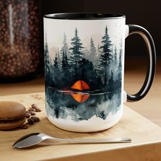 a coffee mug sitting on top of a wooden table next to a spoon and cup