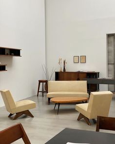 a living room filled with lots of furniture next to a wall mounted shelf and bookcase