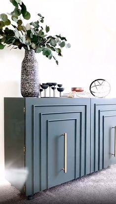 a vase filled with flowers sitting on top of a blue cabinet next to a white wall