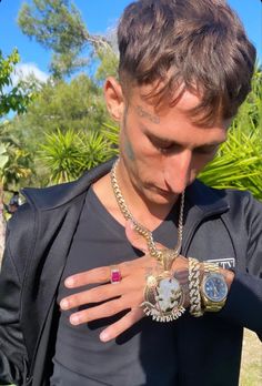 a young man with tattoos on his arm holding onto two bracelets and wearing a black jacket