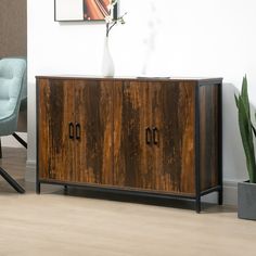 a sideboard with two doors and a vase sitting on top of it next to a chair