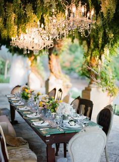 the table is set for an event with chandelier hanging from it's ceiling