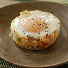 an egg is on top of some kind of food in a brown plate with a green table cloth