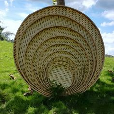 a round wicker basket sitting on top of a lush green field